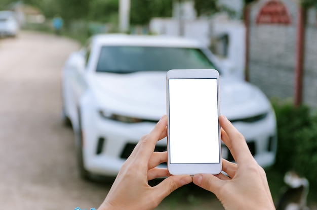 Smartphone vide dans les mains de la femme, dans la voiture blanche de fond