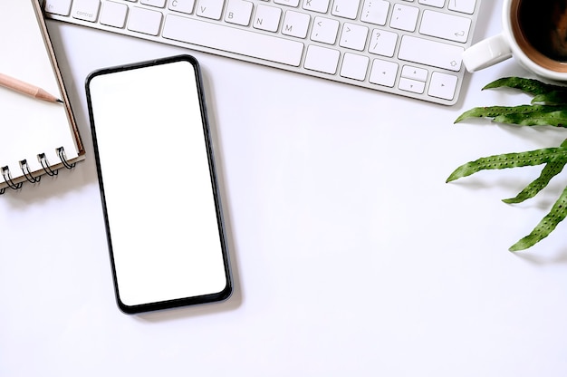 Smartphone vue de dessus avec écran blanc et fournitures de bureau sur fond blanc.