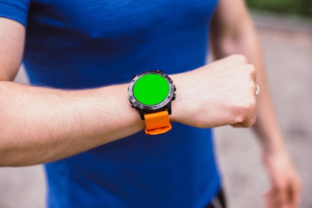 Smartwatch à portée de main du sportif avec écran vert. Montre gadget sport avec écran chromakey