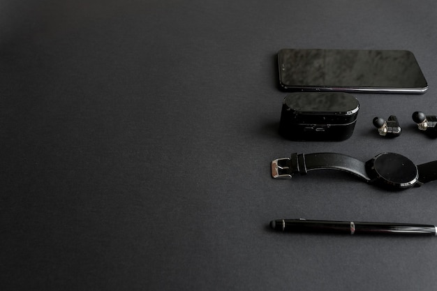 Smartwatch et téléphone avec stylo et casque sur fond monochrome