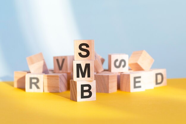 SMB écrit sur des cubes en bois - disposés en pyramide verticale, fond gris et jaune, SMB - abréviation de Server Message Block, concept d'entreprise