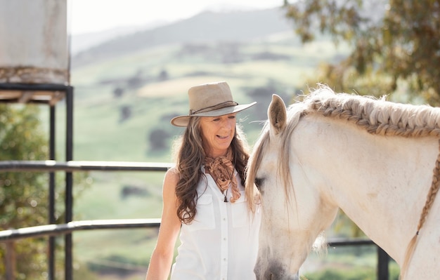 Photo smiley agricultrice avec son cheval au ranch