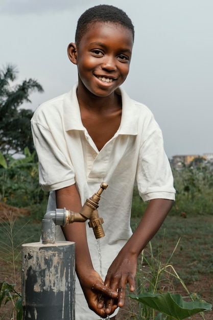 Photo smiley enfant africain se lave les mains