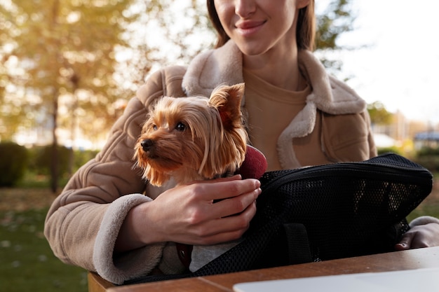 Smiley femme avec chien dans le sac vue de face