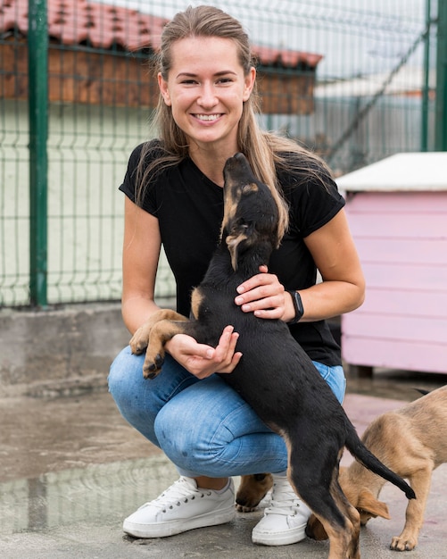 Smiley femme jouant avec des chiens de sauvetage au centre d'adoption