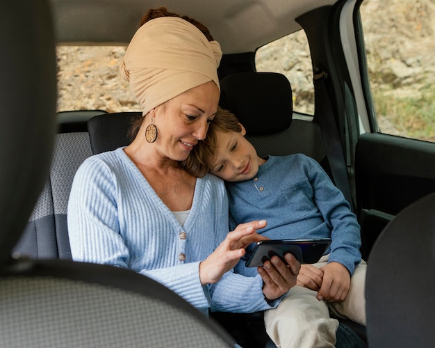 Smiley mère et fils en voiture à l'aide de mobile