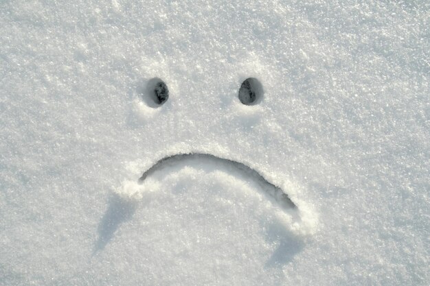 Smiley triste dessiné dans la neige