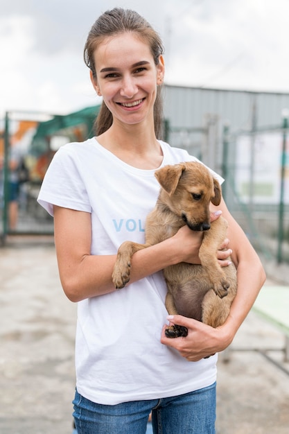 Photo smiley woman holding adorable chien de sauvetage au refuge d'adoption