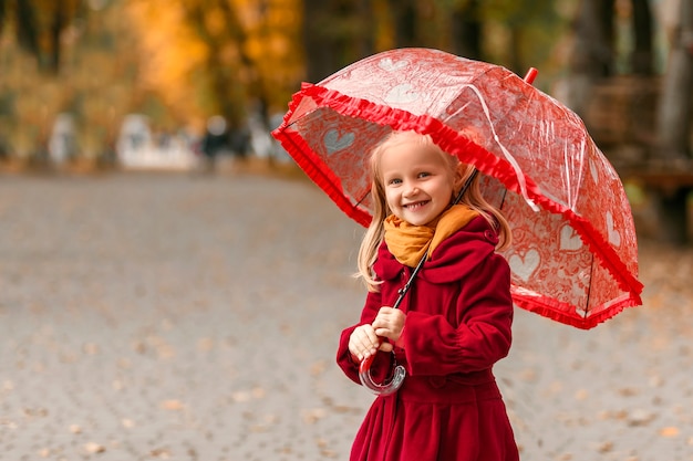 Smilimg enfant debout avec parapluie dans une belle journée d'automne