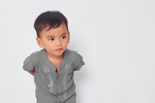 Smiling attractive bambin garçon musulman asiatique regardant l'espace vide isolé sur fond de studio blanc