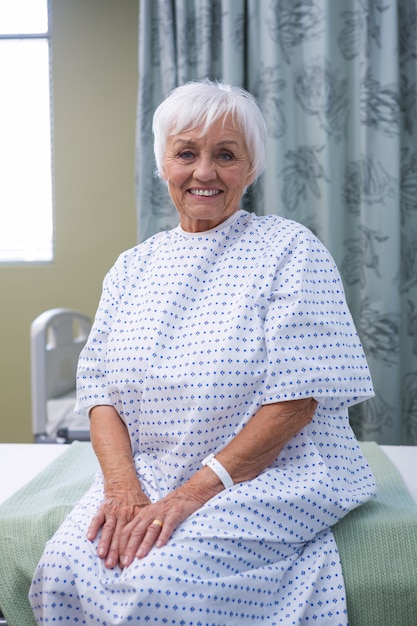 Smiling senior patient assis sur le lit à l'hôpital