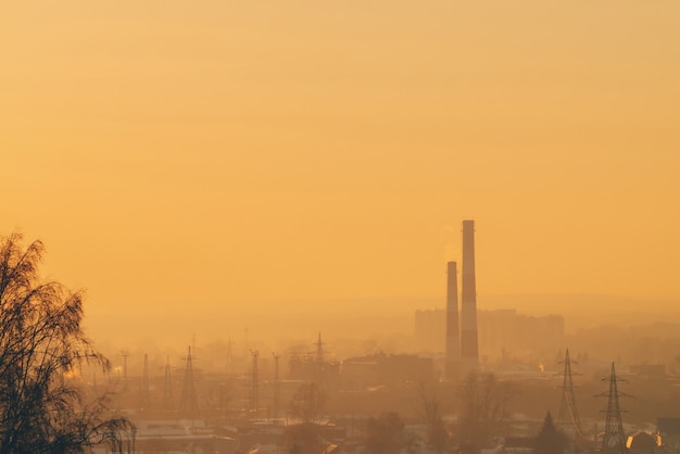 Smog parmi les silhouettes des bâtiments au lever du soleil.