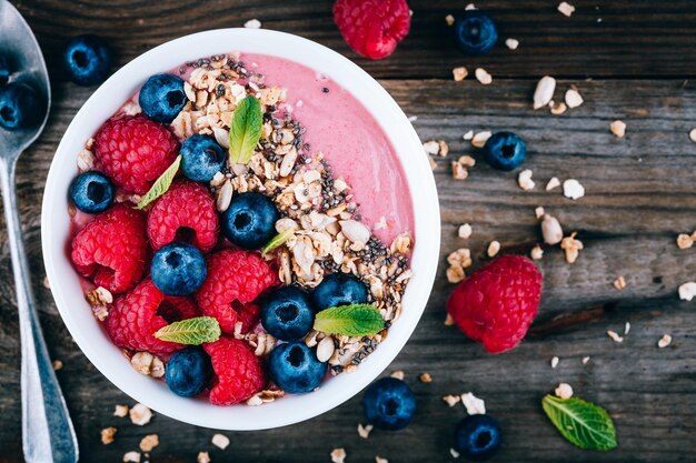 Smoothie Acai et bol de granola avec framboises fraîches et bleuets sur fond de bois