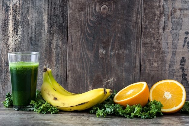 Smoothie au chou frisé, banane et orange sur fond de bois