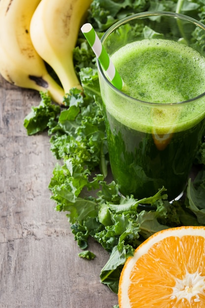 Smoothie au chou frisé, banane et orange sur fond de bois