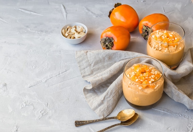 Smoothie au kaki et noix de cajou dans des verres sur fond de béton gris