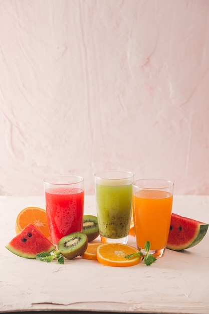 smoothie au kiwi, à l'orange et à la pastèque et divers morceaux de fruits sur la table