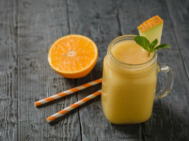 Smoothie Au Melon, Orange Et Banane Fraîchement Préparé Et Deux Pailles à Cocktail Sur Une Table En Bois