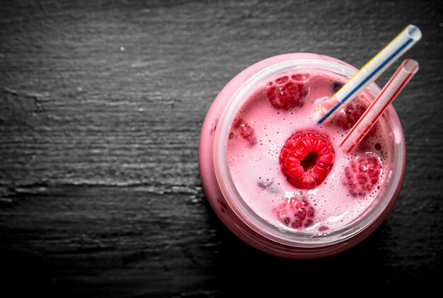 Smoothie aux framboises aux baies entières sur tableau noir.