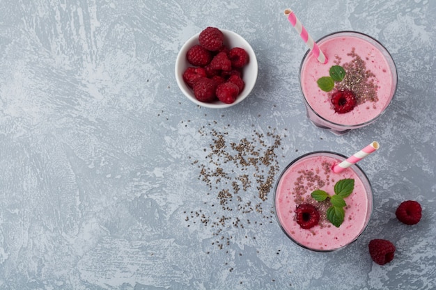 Smoothie aux framboises aux graines de chia et à la menthe dans une tasse en verre sur une table en pierre ou en béton gris clair. Petit déjeuner sain et savoureux. Mise au point sélective.