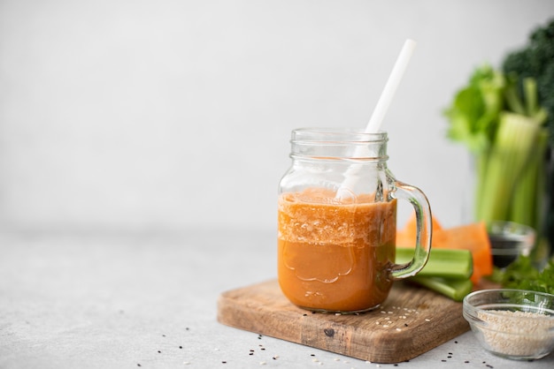 Smoothie aux légumes carottes et céleri aux graines de sésame dans une tasse en verre