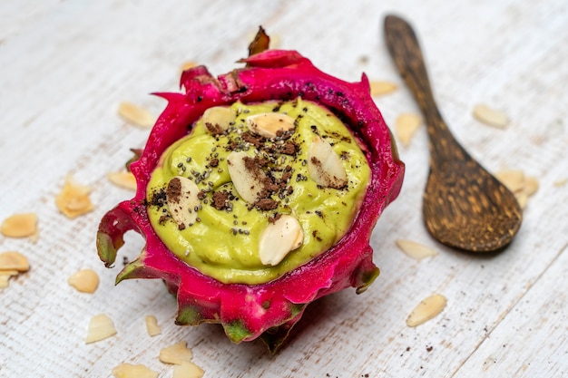 Smoothie à l'avocat vert dans une peau de fruit du dragon avec des flocons d'amande et des graines de chia pour le petit-déjeuner, gros plan. Le concept d'une alimentation saine, superaliment . Bali, Indonésie