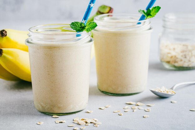 Smoothie à l'avoine à la banane ou milk-shake dans des bocaux en verre sur fond de pierre grise