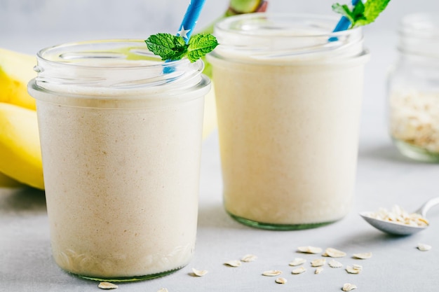 Smoothie à l'avoine à la banane ou milk-shake dans des bocaux en verre sur fond de pierre grise