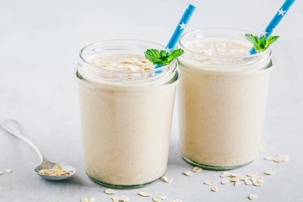 Smoothie à l'avoine à la banane ou milk-shake dans des bocaux en verre sur fond de pierre grise