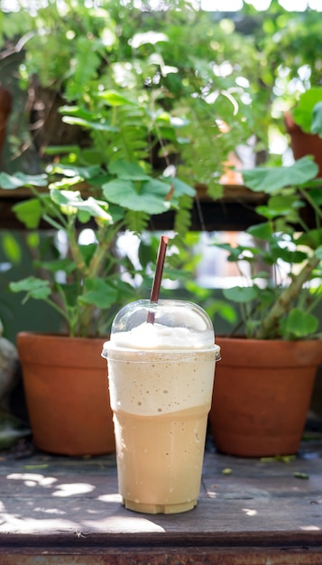 Smoothie café sur une table en bois et fond de la plante.