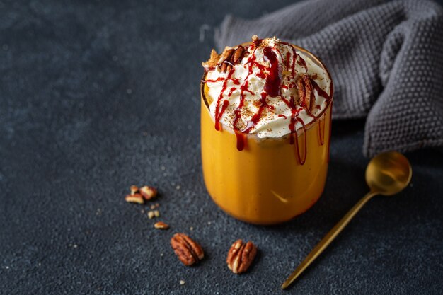 Smoothie à la citrouille servi avec crème fouettée et caramel en verre. Fermer