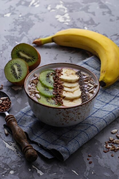 Smoothie dans un bol avec des graines de banane, kiwi, chia, lin et tournesol