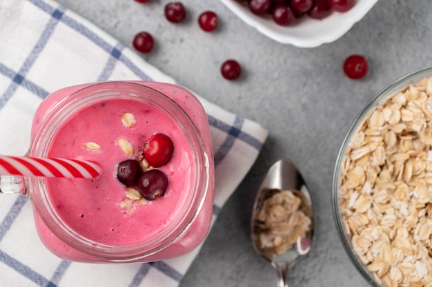 Photo smoothie fraîchement fait maison avec canneberges, flocons d'avoine et yogourt dans un pot de tasse sur. vue de dessus, flatlay