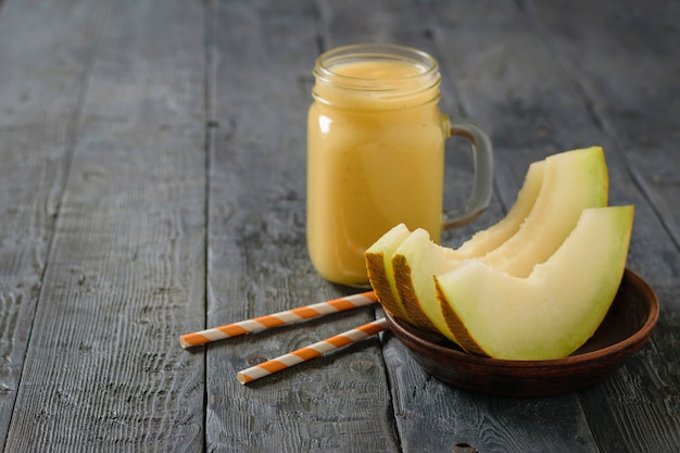 Smoothie fraîchement melon, orange et banane et trois tranches de melon sur une table