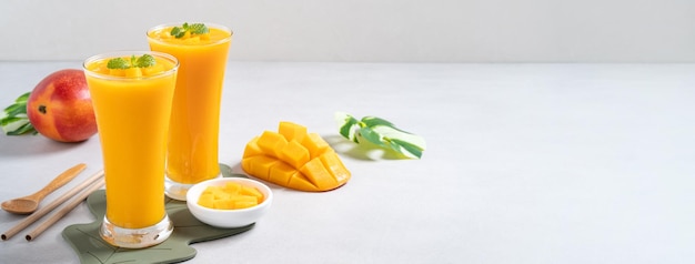 Smoothie frais et délicieux au jus de mangue dans une tasse en verre sur fond de table gris