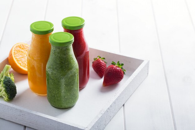 Smoothie fraise, orange et brocoli frais dans des bouteilles de fruits et légumes