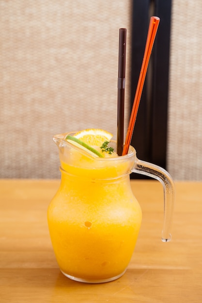 Smoothie de jus d&#39;orange en pot de verre avec starw sur la table en bois