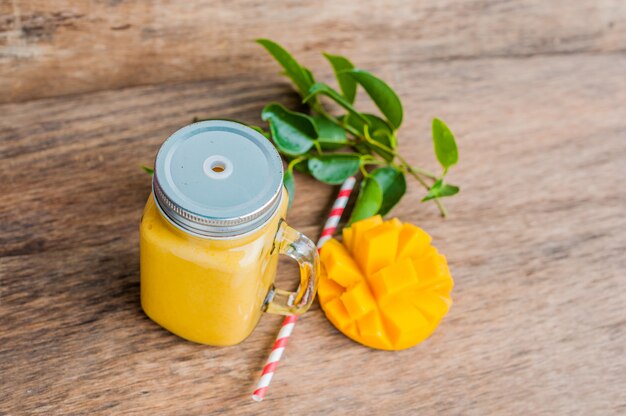 Smoothie juteux à la mangue dans un bocal en verre avec de la paille rouge à rayures