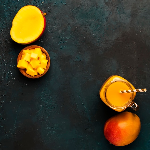 Smoothie à la mangue dans un bocal en verre avec des fruits frais sur fond bleu copie espace vue de dessus