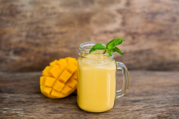 Smoothie à la mangue dans un pot Mason en verre et mangue sur le vieux fond en bois. Shake à la mangue.