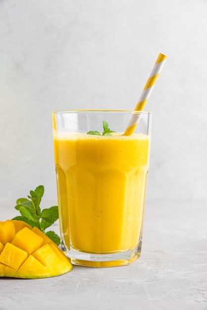 Smoothie à la mangue jaune fraîche dans un verre avec des fruits frais de paille et de la menthe Boisson tropicale d'été