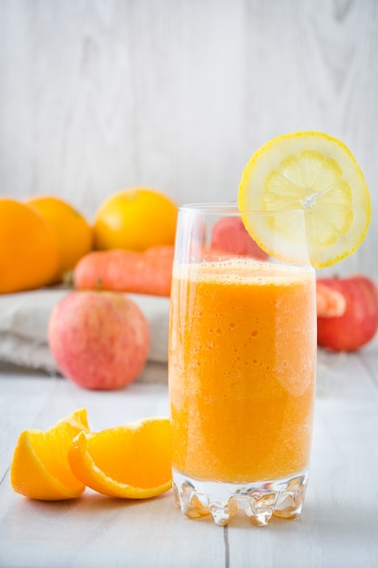 Smoothie orange, pomme et carottes sur table en bois blanc