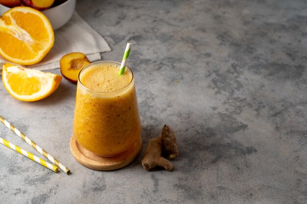 Smoothie orange en verre fait avec du gingembre pêche et de l'espace de copie orange