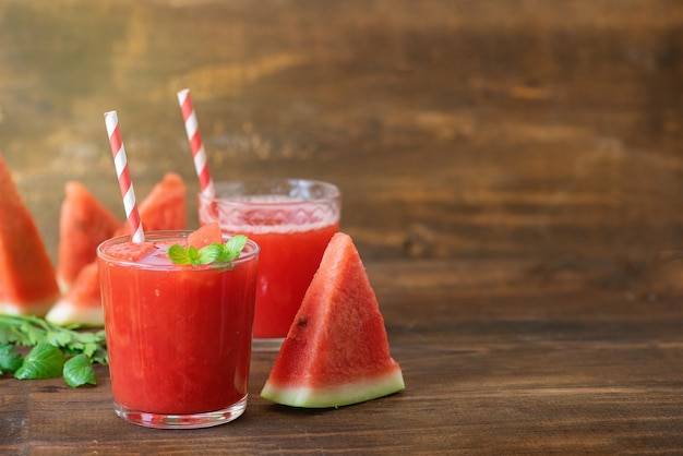 Smoothie pastèque dans des bocaux avec des tranches de pastèque fraîche sur fond de bois gris. Copiez l'espace.