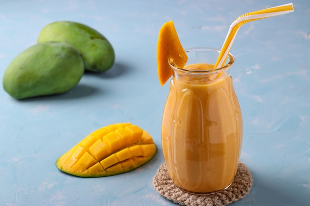 Smoothie tropical fait maison de mangue sur une surface bleu clair, orientation horizontale