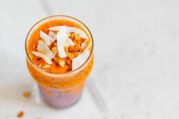 Le smoothie végétalien orange et violet est fabriqué à partir de noix de crème de noix de coco à l'argousier de bleuets et de chia sur fond blanc Le concept d'aliments et de boissons d'été sains