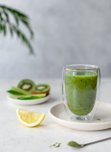 Smoothie vert coloré aux épinards, céleri, kiwi, citron et poudre de superaliment vert dans un verre à double paroi. nourriture végétalienne.