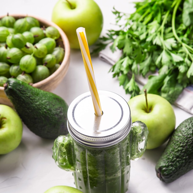 Smoothie vert dans un verre en forme de cactus parmi les ingrédients verts