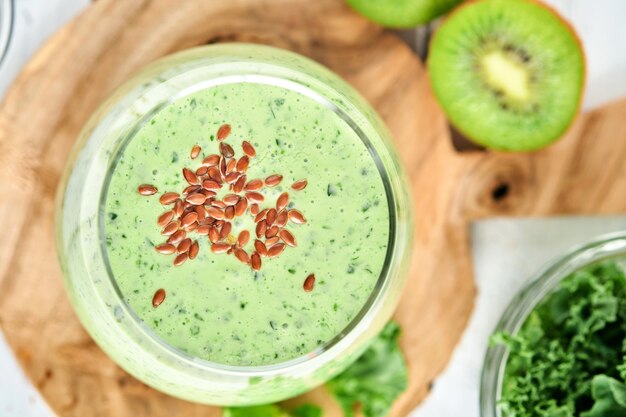 Smoothie vert détox au chou frisé, épinards et kiwi sur une ardoise gris clair