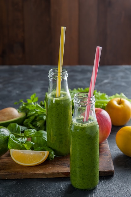 Smoothie vert de différents légumes et fruits sur table en bois